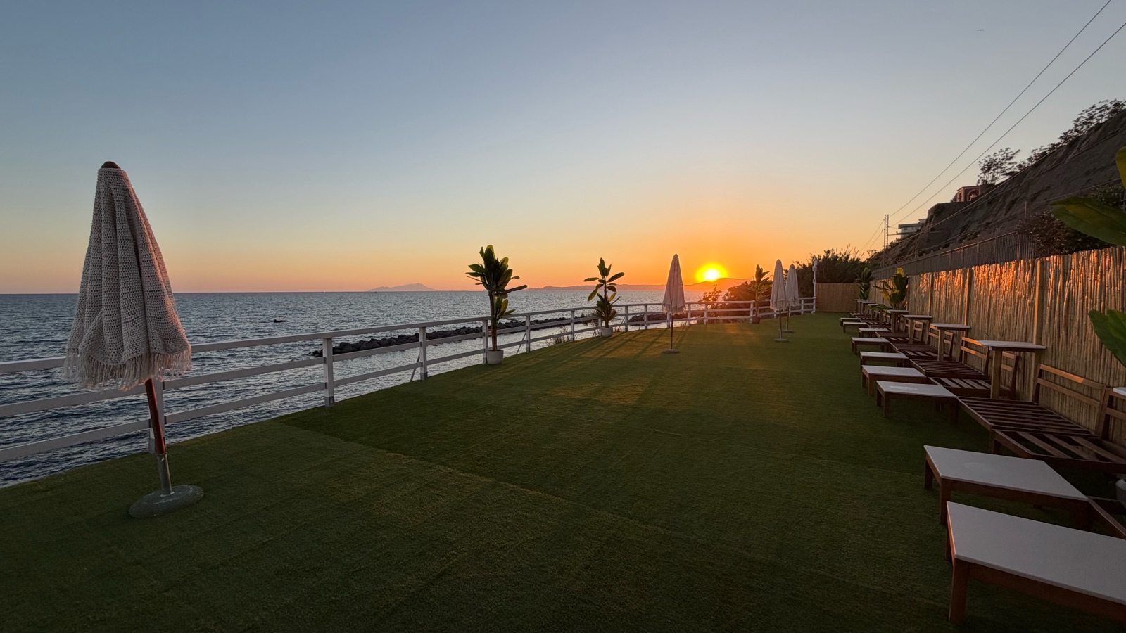 La terrazza panoramica sul promontorio al tramonto, con ombrelloni e lettini