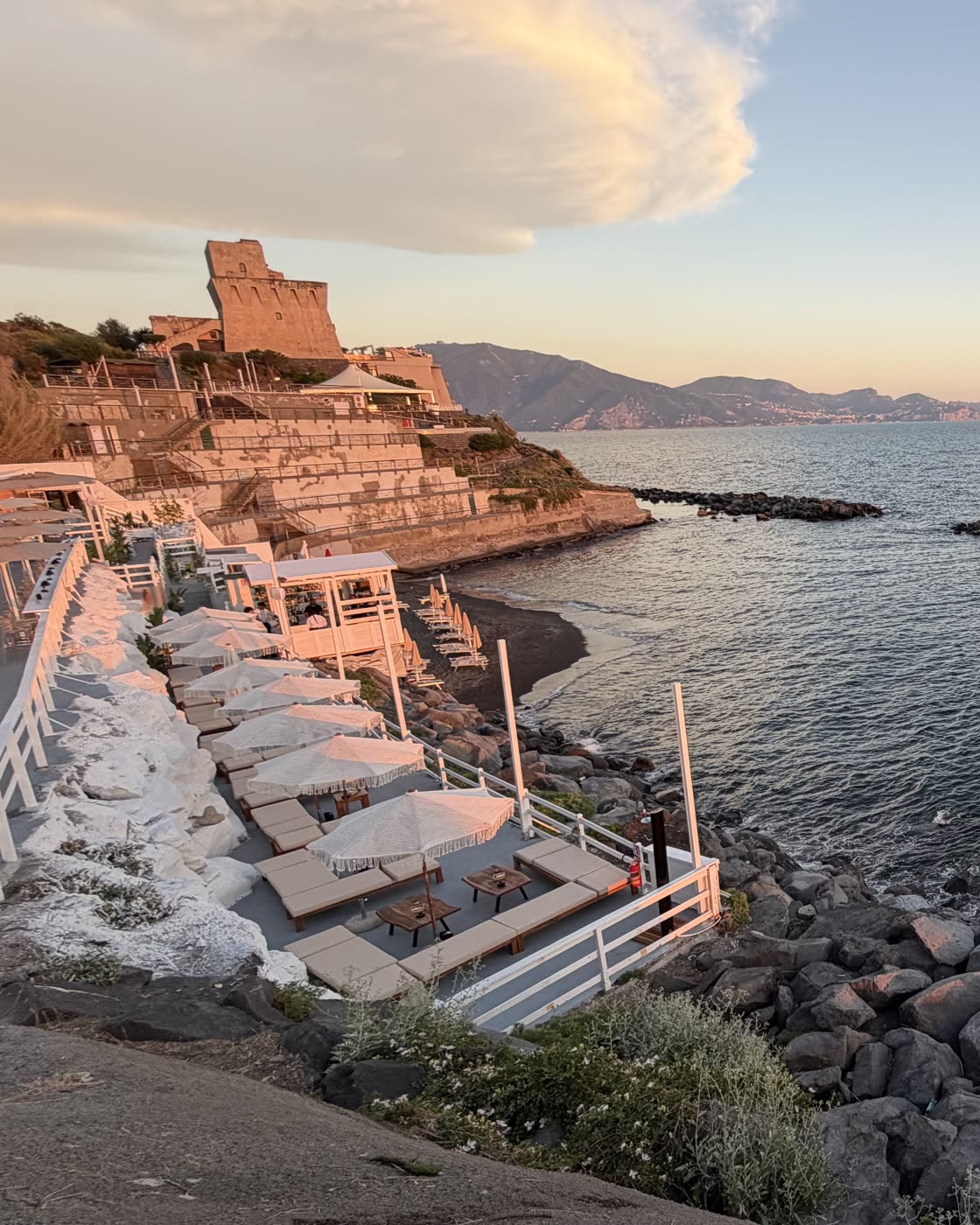 Lettini e ombrelloni su una cala rocciosa affacciata sul mare turchese